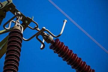 Close-up of insulators on high voltage pylons against the background of blue sky. Made in a sunny day, deep blue skies