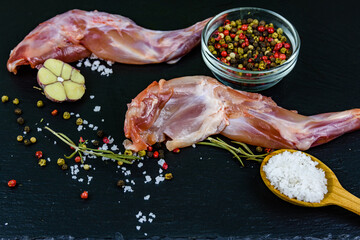Rabbit meat with pepper, rosemary, salt and garlic on a slate board