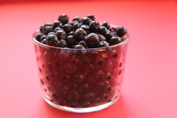 berry still life blueberries or currants in a glass on a red background with a place for text and a copyspace view from the side