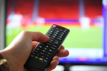 Fußball im TV schauen. Mann mit Fernbedienung im Vodergrund.