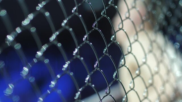 iron cage for mixed combat fighters. A fighter in gloves warms up before a fight