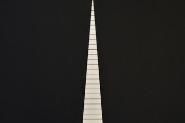  Abstract white striped long narrow triangle in the middle of a black background. The concept of a life path, striving upward for success and prosperity.