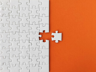 Missing piece of the puzzle, white puzzle pieces on orange background	
