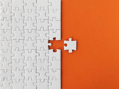 Missing piece of the puzzle, white puzzle pieces on orange background	
