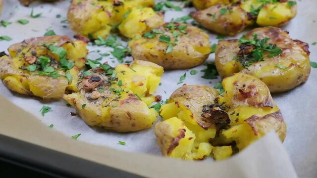 Baked smashed potatoes with herbs on baking sheet.