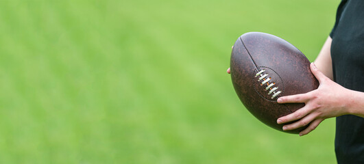 Woman holds a rugby ball, isolated on a green background