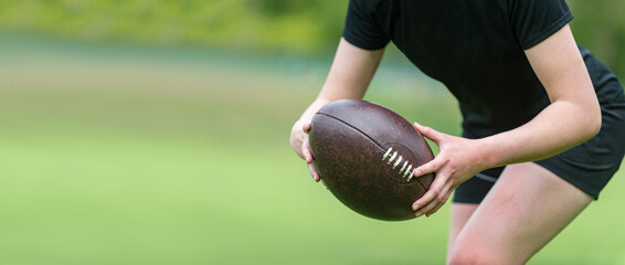 Woman holds a rugby ball, isolated on a green background. Woman sport concept