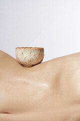 Cropped shot of traditional tea bowl on graceful female body. The beige ceramic bowl with glazed...