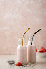 Two bottles with strawberry blended smoothie and chia seeds
