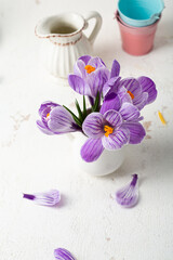Spring flowers in jug on white table, holiday concept