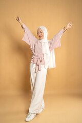asian muslim woman euphoric raising arm on studio shot