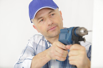 mid-adult man drilling hole in wall