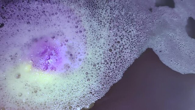 A ball of bath salt dissolving in water alongside an essential oils for better sleep | Relaxing fizzy bath bomb