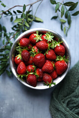 Strawberries in a bowl surrounded by greens