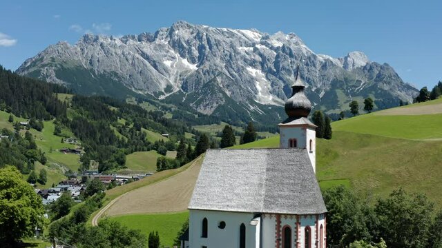 Parish church of Dienten with Hochk&ouml;nig mountain on the background. Pinzgau, Salzburg, Austria. Aerial view.