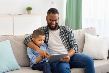 African Boy And His Father Using Digital Tablet At Home