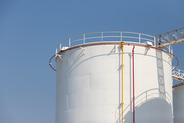 white fuel tanks against blue sky, white steel petroleum silo with rust, liquid metal container.