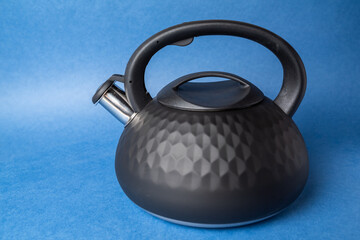 Naklejka na ściany i meble black metal teapot with whistle and plastic handle on blue background