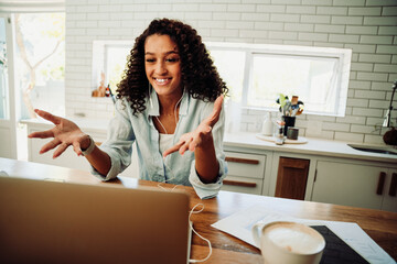 Mixed race female student engaging on video call on laptop sitting in kithcen