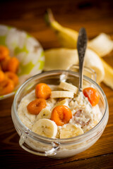 cooked boiled sweet oatmeal with with dried apricots and bananas in a bowl