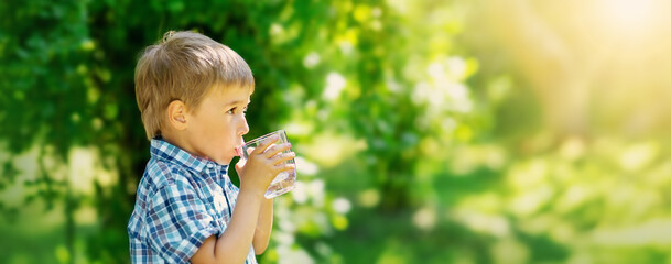 Cute boy drinking a glass of pure water in nature.