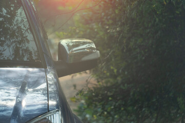 Abstract and blur of front car with warm light orange color. Car parking beside the tree.