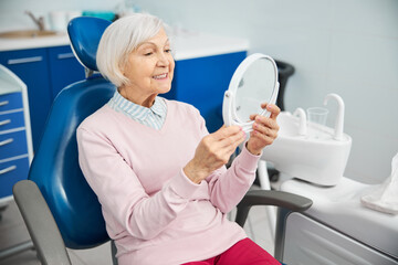 Elderly citizen picking the table mirror and looking at herself