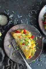 Healthy breakfast food: stuffed omelette with vegetables on dark background. Top view with copy space.