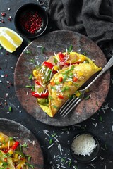 Healthy breakfast food: stuffed omelette with vegetables on dark background. Top view with copy...
