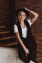 Fototapeta premium Attractive stylish blonde woman in black hat smiling posing at camera.Soft selective focus, defocus, artistic noise.