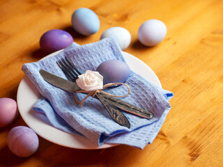 Naturally colored stylish Easter eggs in a plate, decorative flowers, on a wooden table