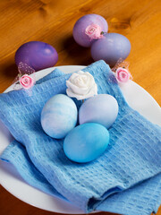 Naturally colored stylish Easter eggs in a plate, decorative flowers, on a wooden table