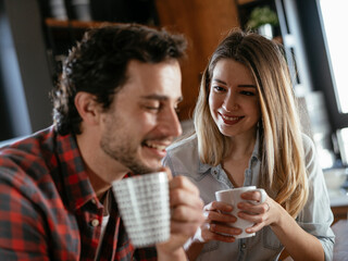 Loving couple drinking coffe in the kitchen. Happy smiling wife enjoy in the morning with her husband.