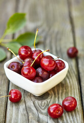Cherry in a bowl on grey wooden old table. Ripe ripe cherries. Sweet red cherries.