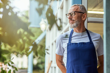 Middle aged caucasian man in apron looking sideways - Powered by Adobe