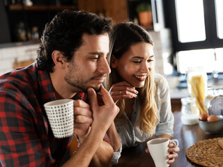 Loving couple drinking coffe in the kitchen. Happy smiling wife enjoy in the morning with her husband.