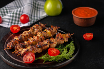 Chicken skewers with apples and vegetables on a black background
