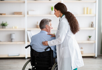 Elderly patient with physical disability receiving medical help from young physician during covid...