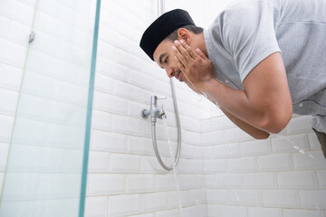 portrait of young Muslim man perform ablution (wudhu) before prayer at home