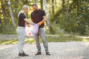 Fototapeta premium Couple collects garbage in garbage bags in park