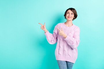 Photo of shiny adorable young lady dressed purple pullover looking pointing fingers empty space isolated teal color background