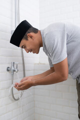portrait of young Muslim man perform ablution (wudhu) before prayer at home