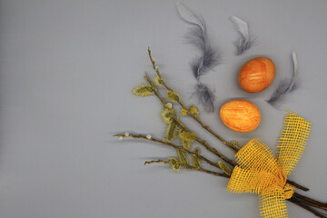 branches of willow with yellow ribbon, gray feathers and Easter eggs 
