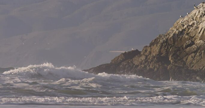 Pacific ocean waves crashing the coast clifs at San Francisco during sunset