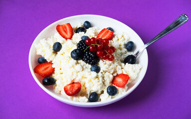 Cottage cheese, curd cheese or tvorog with fresh berries ober purple background