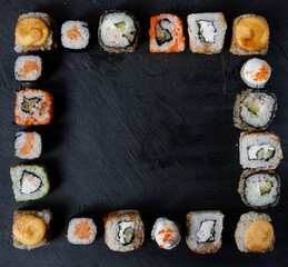 A variety of sushi with wooden desk on black slate background. Asian food frame. Top view. Copy space, overhead, flat lay