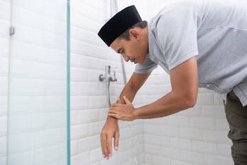 portrait of young Muslim man perform ablution (wudhu) before prayer at home