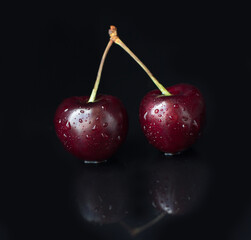 Close-up of cherry berries on a black background. Summer still life
