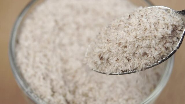 Natural herbal food supplement psyllium husk in a spoon. Falling in slow motion. Wellness concept