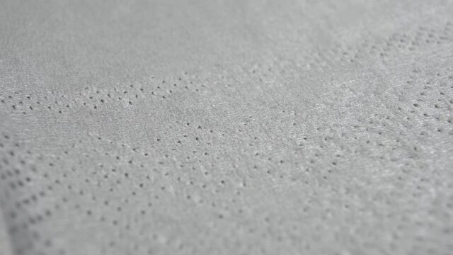 Embossed dotted texture of gray paper napkin. Macro. Dolly Shot